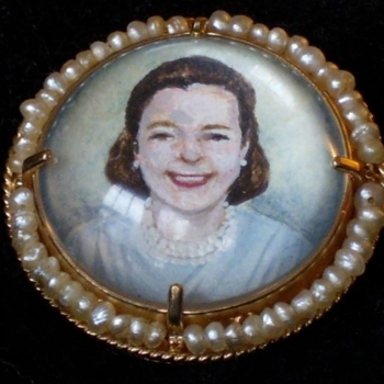 A broche feauring a tiny portait painted on mother of pearl.
